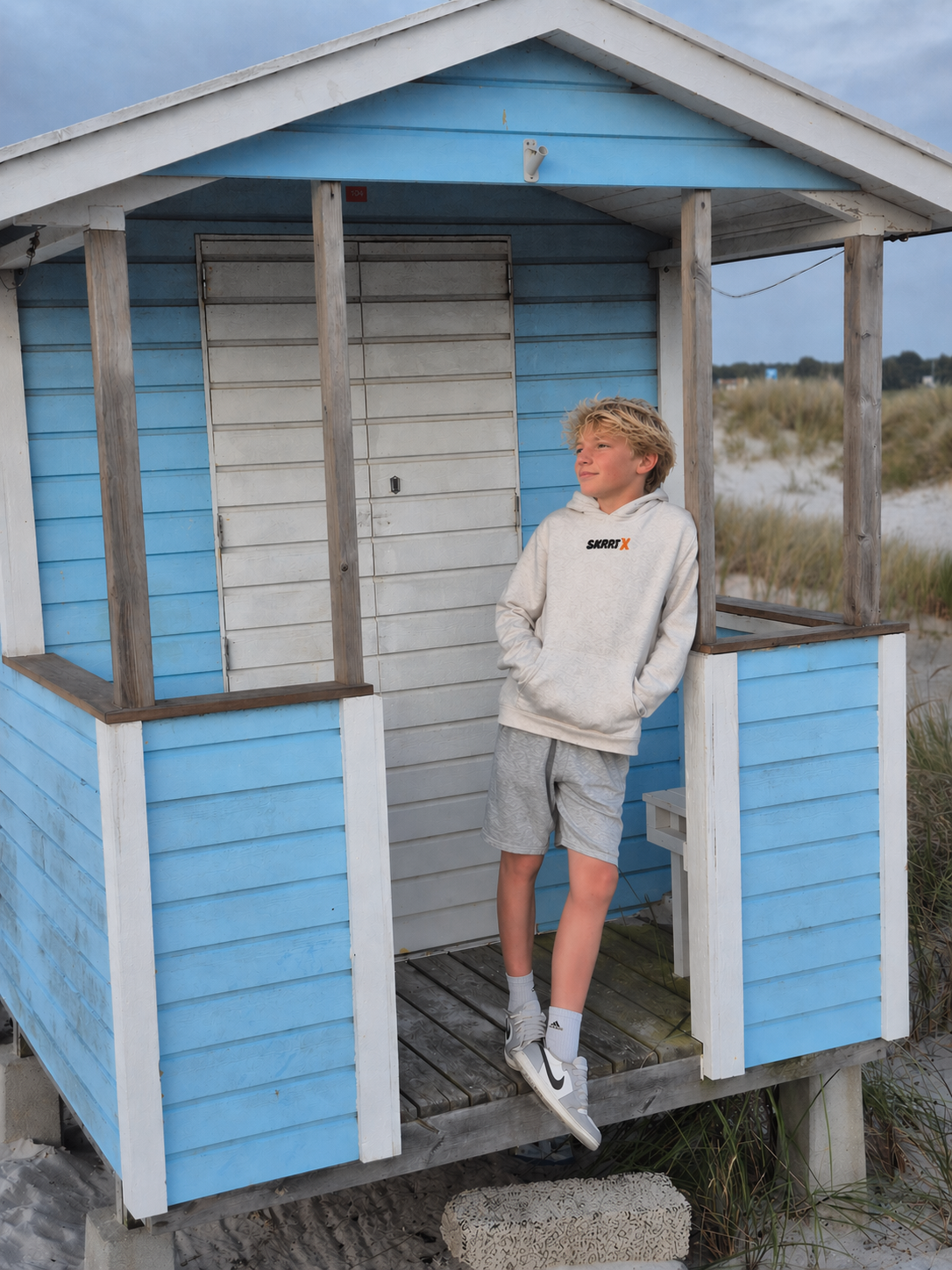 Back graphic of the SKRRTX daisy hoodie against hand-painted turquoise surf signs